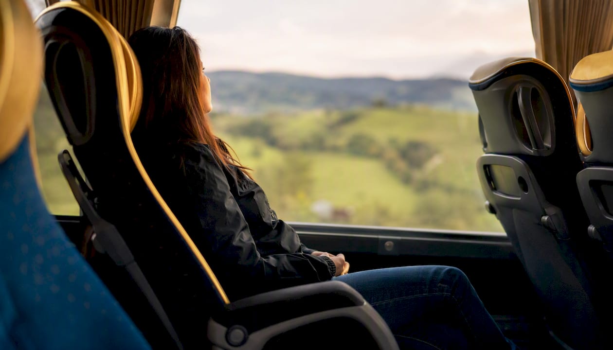 Passenger seated inside coach looking out window