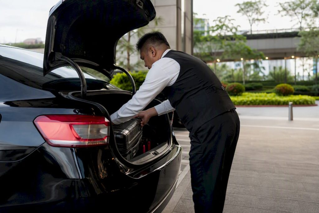 Chauffeur loading luggage into vehicle before zoo trip
