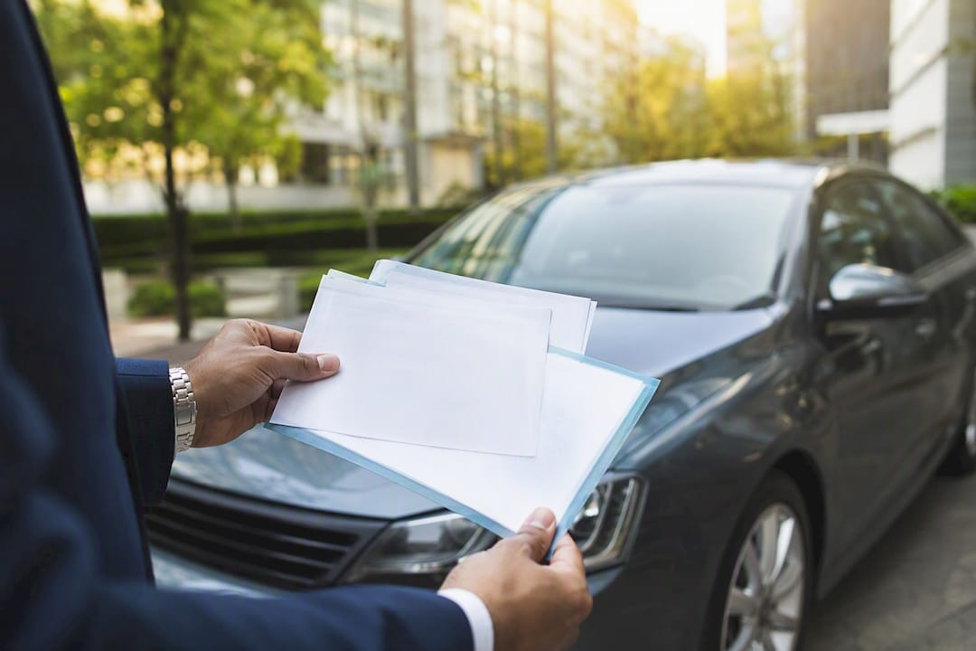 Chauffeur holding vehicle insurance and road tax papers