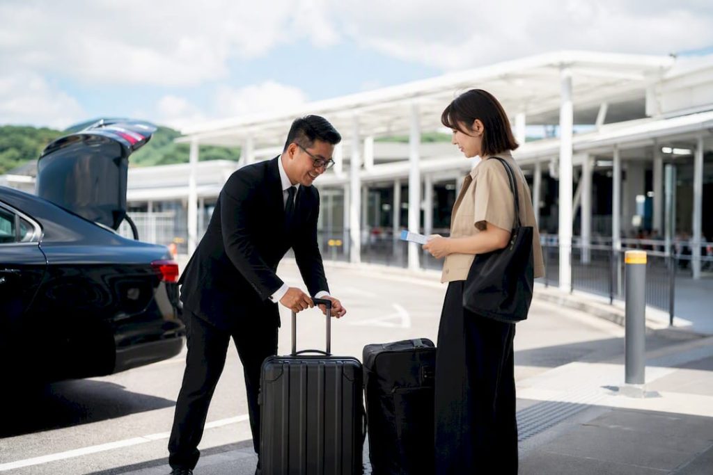 Chauffeur loading luggage at ferry terminal curbside